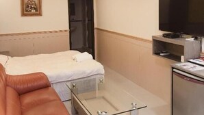 A hotel room with a bed, a sofa, a glass-top coffee table, a TV, and an air conditioning unit. - Taipei 101 Yurmans House (Taipei)