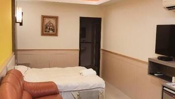 A hotel room with a bed, a sofa, a TV, and a small table.