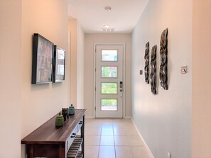 A hallway with a wooden bench, framed pictures, and a door with frosted glass panels.