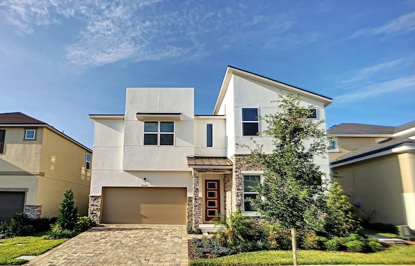 A modern two-story house with a garage, a stone facade, and a well-maintained lawn.