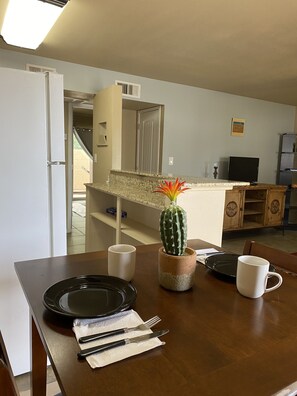 Enjoy meals in this cozy dining area with a table set for two, a potted cactus, and a TV for entertainment.