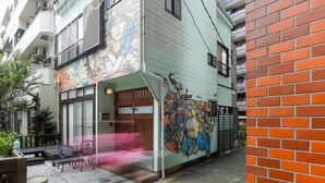 Un bâtiment dont la façade extérieure est ornée d’une fresque colorée, doté d’une entrée abritée et d’un petit espace extérieur aménagé en coin salon.