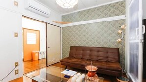 Un salon moderne avec un canapé en cuir marron, une table basse en verre et un service à thé décoratif.