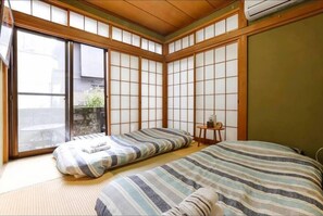 A traditional Japanese-style room with tatami flooring, sliding doors, and a bed with striped bedding. - Nishi shinjyuku wa-an homestay (Tokyo)
