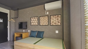 Une chambre à coucher moderne avec un lit en bois, un téléviseur et trois œuvres d’art murales aux motifs géométriques.