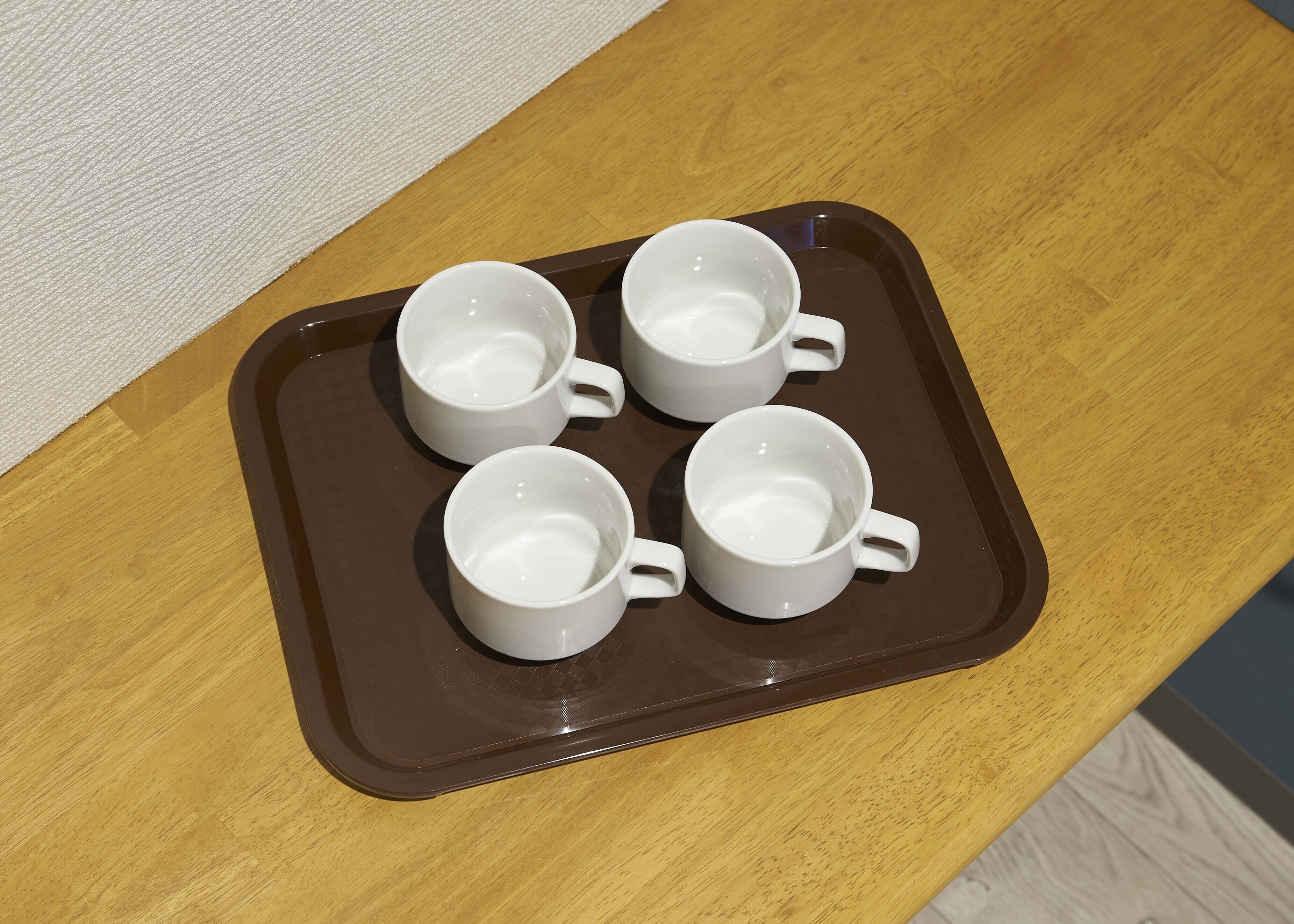 A tray with four white mugs on a wooden table.