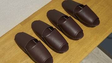 Four brown leather slippers on a wooden table.