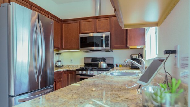 Una cocina con electrodomésticos de acero inoxidable, armarios de madera y encimera de granito.