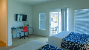 Un dormitorio con dos camas, un escritorio, una silla y un televisor.