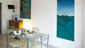 A dining area with a glass table, metal chairs, and a painting on the wall. - Cosy apartment for 4 people with WIFI, TV and patio (Imperia)