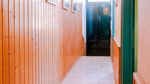 A wooden hallway with tiled flooring, framed pictures on the wall, and a hanging light fixture. - TREM HOUSE - LOCATED IN OLD CITY - FARO (Faro)