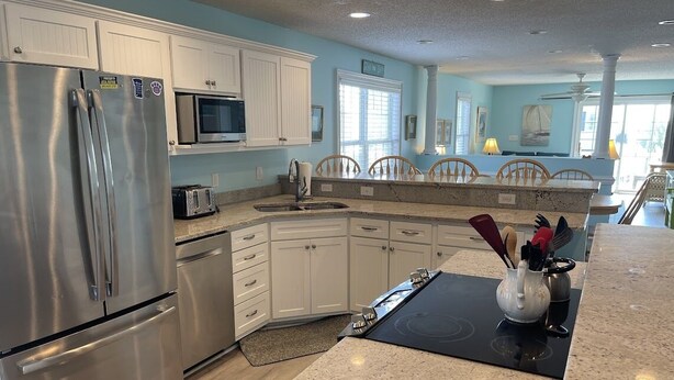 A kitchen with white cabinets, stainless steel appliances, and a granite countertop. - Come On In (Downstairs) - Second Row in Garden City Beach (Garden City Beach)
