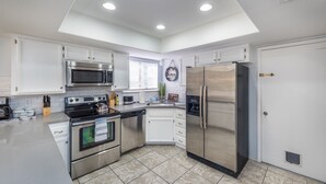 A modern kitchen with stainless steel appliances, white cabinetry, and a tiled floor. - Charming & Stylish home can accommodate 8 guests! (Henderson)