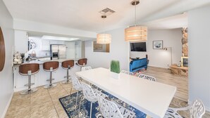 A modern kitchen with white cabinets, a central island with bar stools, and pendant lighting. - Charming & Stylish home can accommodate 8 guests! (Henderson)