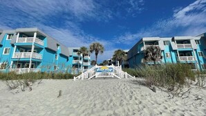 Un hotel frente a la playa con valla blanca y un letrero que dice "Beach House".