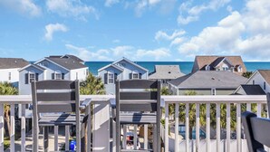 A view of a beachfront property with multiple houses, a wooden deck, and a clear blue sky. - Southern Faire - Second Row in Surfside Beach (Surfside Beach)