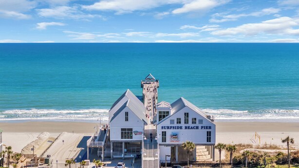 A beachfront pier with a sign reading "Surfside Beach Pier" and a building with a tower. - Southern Faire - Second Row in Surfside Beach (Surfside Beach)