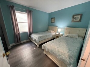 A bedroom with two beds, a window with curtains, and a door with a brass handle. - Carolina Shores II 2206 - Oceanfront Complex (Oceanview Unit) in Garden City Beach (Garden City)