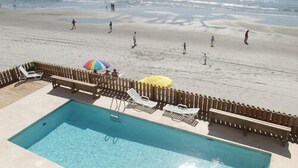 Een zwembadgedeelte met een houten terras, ligbedden en parasols.