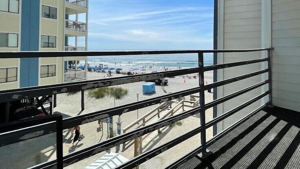 Een balkon met uitzicht op een strand en een gebouw met meerdere verdiepingen en balkons.