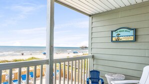 A balcony with a view of the beach, a sign reading "Our Beach House", and a pool area with lounge chairs. - Captain's Walk III 1C - Oceanfront in Garden City Beach (Garden City)