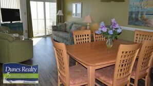 Uma área de refeições com uma mesa e cadeiras de madeira, um vaso com flores e um quadro na parede.