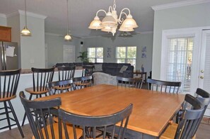 Enjoy meals in this stylish dining area with a large table, comfortable seating, and a modern chandelier.