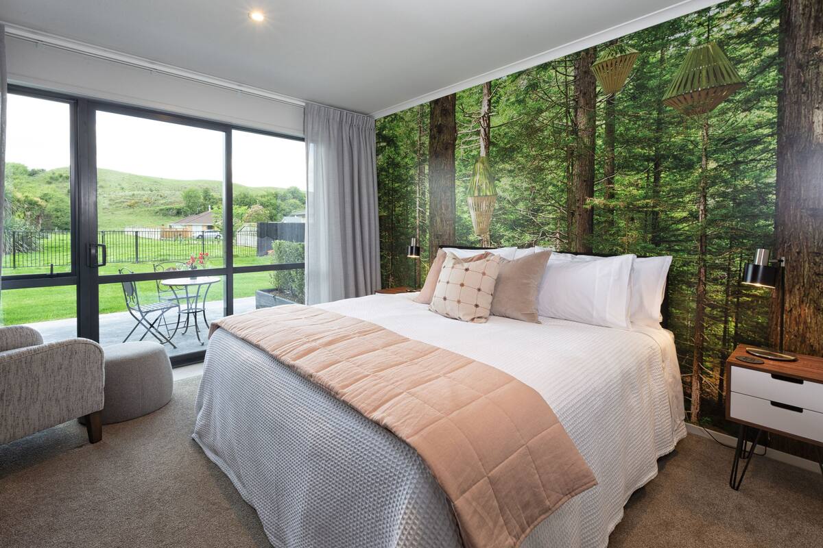 A bedroom with a large bed, a view of the outdoors, and a balcony.