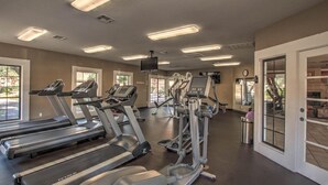 Un gimnasio con cintas de correr, elípticas y una pantalla de televisión.