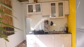 Una cocina compacta con gabinetes blancos, una estufa a gas y un lavamanos.