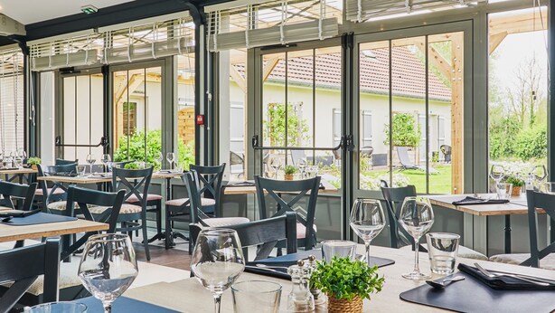 A restaurant with tables set for dining, large windows, and a view of the outside. - Domaine Les Saules (Favieres)