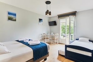 Une chambre d’hôtel avec deux lits, un bureau, une chaise, une télévision et un balcon avec vue.