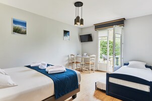 Habitación de hotel con dos camas, un escritorio, una silla, televisión y balcón con vistas.