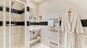 Une salle de bain moderne équipée d’une douche, d’un lavabo et d’un porte-serviettes.