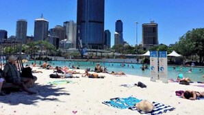Une plage avec une piscine et, en arrière-plan, la silhouette d’une ville.