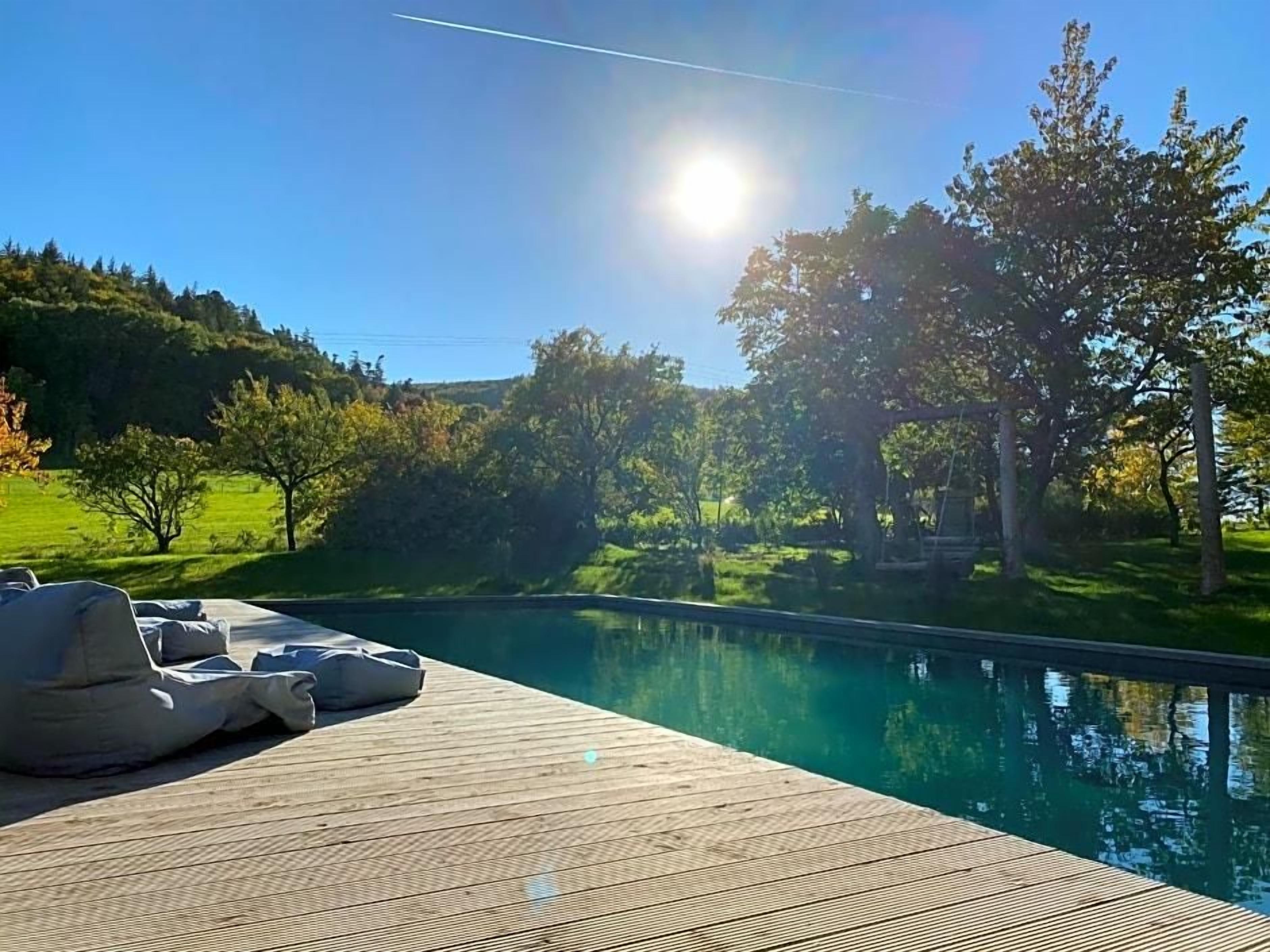Eine Holzterrasse mit Liegestühlen und einem Schwimmbecken.