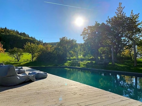 A wooden deck with lounge chairs and a swimming pool.