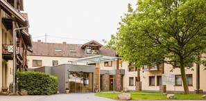 Ein Gebäude mit Glastür, Steinsäulen und einem Baum im Vordergrund.