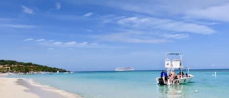 Na praia, areia branca, espreguiçadeiras, guarda-sóis
