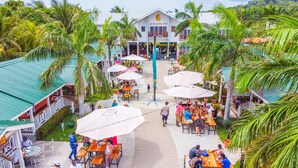 A resort with outdoor dining areas, palm trees, and a building with a sign reading "La Placita Inn". - La Placita Inn (Roatan)