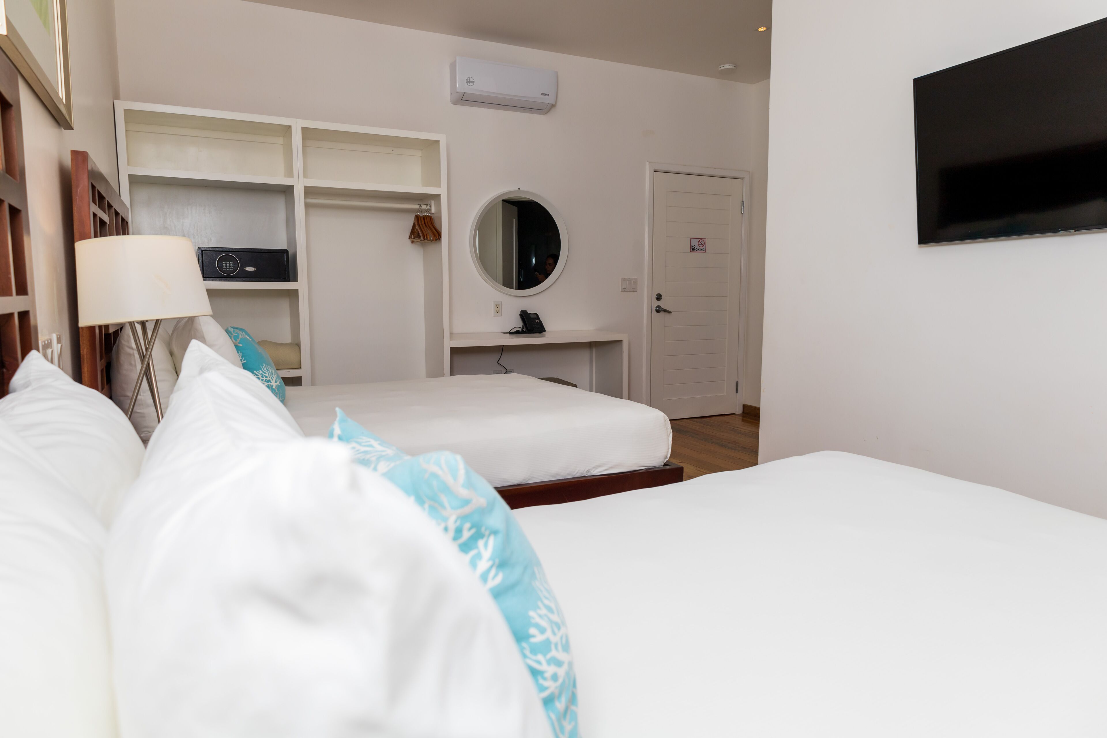 A hotel room with two beds, a TV, a mirror, and a wardrobe.
