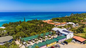 An aerial view of a coastal resort with multiple buildings, a clear blue sky, and the ocean in the background. - La Placita Inn (Roatan)