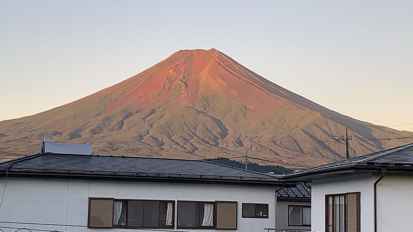 A building with a sloped roof and multiple windows, located in front of a mountain.