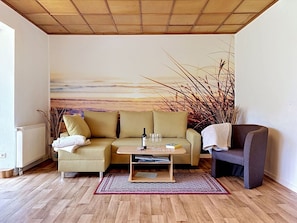 A living room with a beige sofa, a small wooden coffee table, a dark armchair, a radiator, and a large abstract painting on the wall. - Wonderful private villa for 6 guests with WIFI, TV and terrace (Godern)