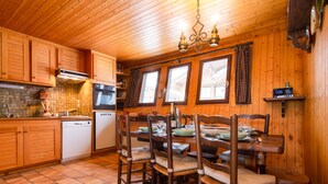 Un interior de madera con zona de cocina, mesa de comedor, sillas y estufa empotrada.