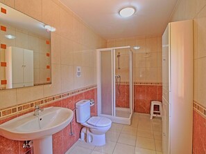 A bathroom with a sink, toilet, and shower area.