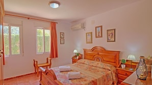 A bedroom with a wooden bed, a chair, a nightstand, a lamp, and a window with curtains. - Wonderful private villa for 11 people with private pool, A/C, WIFI, TV, terrace and pets allowed (Benissa)