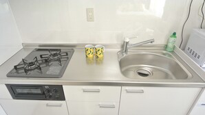 A kitchen with a gas stove, a sink, and a dishwasher. - Kukuru House 3 (Naha)