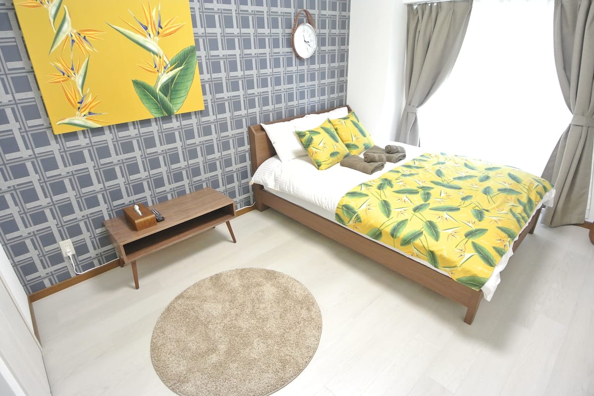 Un dormitorio con cama, mesita de noche y un reloj de pared.
