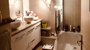 Un baño moderno con un espejo grande, un lavamanos, una bañera y una zona de ducha.